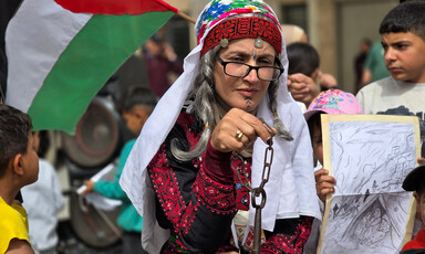 A woman holds a key on a chain, while children around her wave drawings and flags
