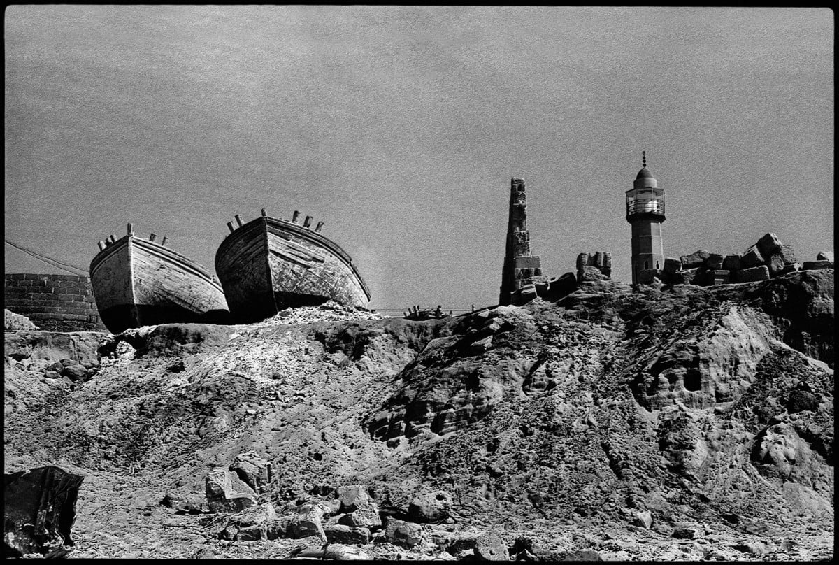 Two boats on a desolate hilltop with a minaret in the background