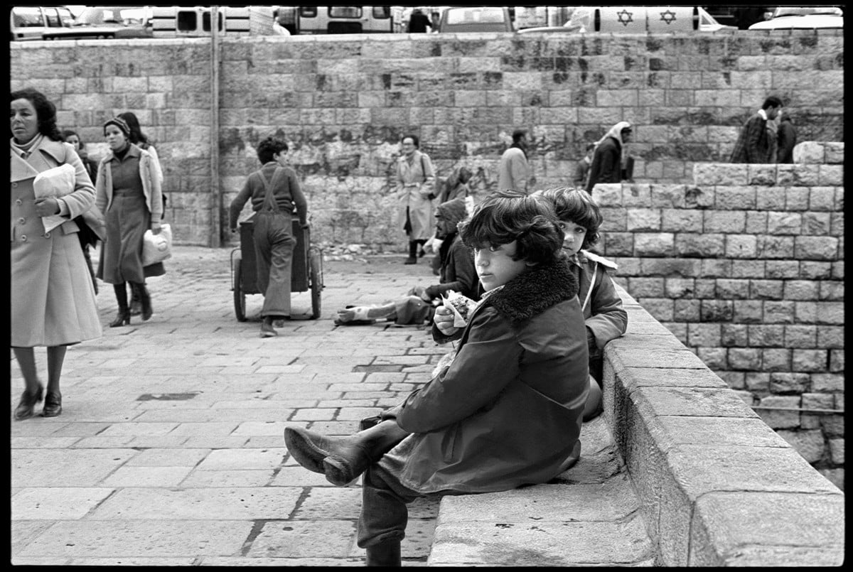 Two children sit on stone bench in front of Damascus Gate