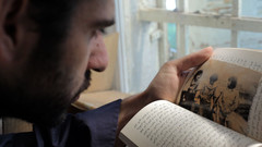 Man looks at Arabic-language book and vintage photograph of armed men