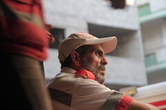 Profile of bearded man wearing paramedic's uniform and cap sitting in front of building