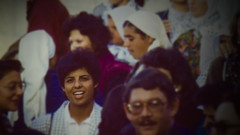 Smiling young woman stands among crowd of men and women