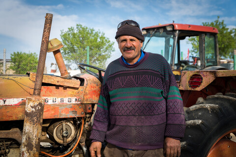 Smiling middle-aged man stands in front of farming equipment