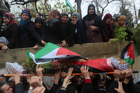 Mourning women look down on youth's body as he is carried in funeral procession