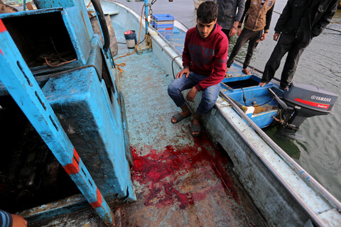 Man sits on edge of ship near pool of blood