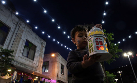 Child holding up a lantern and looking at it. 