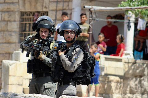 Two soldiers hold rifles in front of home