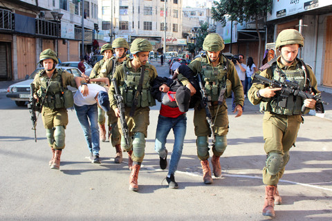 Armed soldiers detain two handcuffed men 