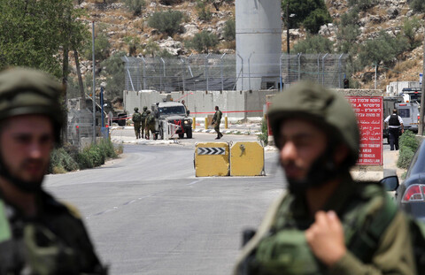 Soldiers stand n front of military tower and roadblocks