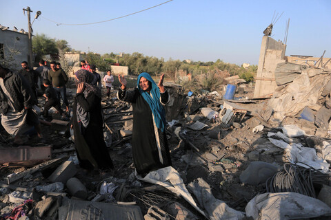 Woman throws her hands in the air while standing on rubble