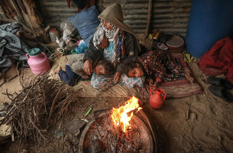 A woman and two children sitting near fire