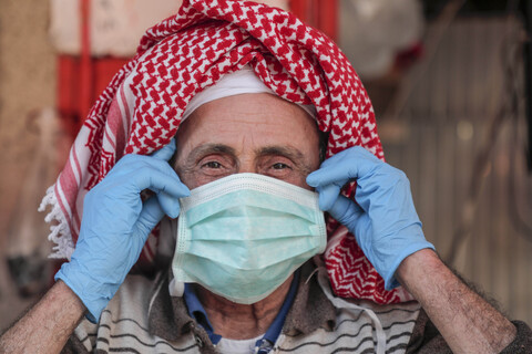 Man wearing headscarf adjusts protective mask on his face