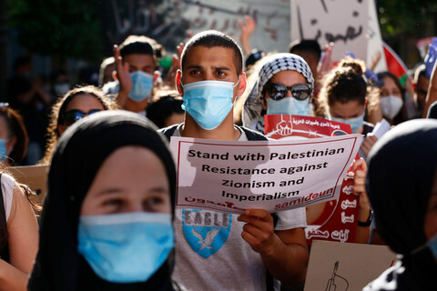 People wearing protective masks hold signs at protest 