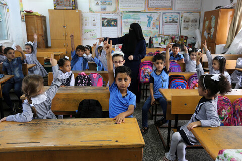 Children raise their hands in a classroom