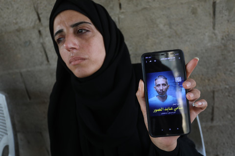 A woman holds up a phone with a picture of a man