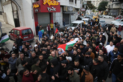 Body shrouded in Palestinian flag is carried on stretcher through city street by crowd of dozens