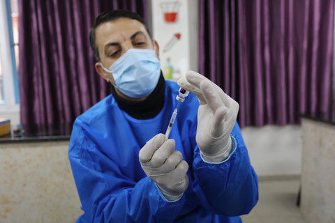 Man wearing mask and gloves holds a syringe 