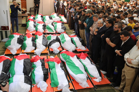 A funeral scene, with a large number of corpses wrapped in flags 