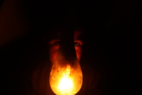 A lamp covers the face of a child amid a general scene of darkness 