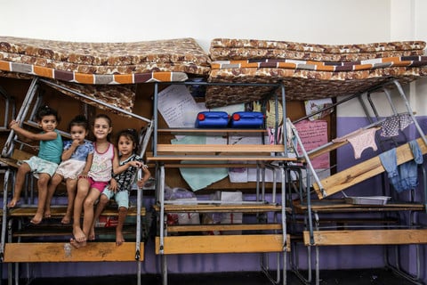 Children sit on stacked up furniture and mattresses