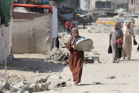 A number of people walk through an area that has been attacked by Israel in southern Gaza 