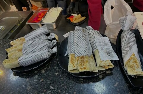 Plates of shawarma in black and white checkered wrapping paper 