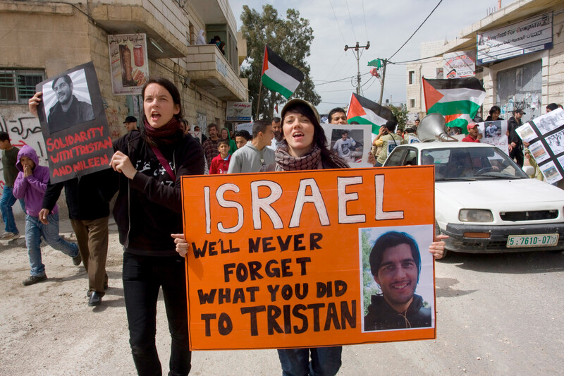 Activists march holding signs in solidarity with Tristan Anderson