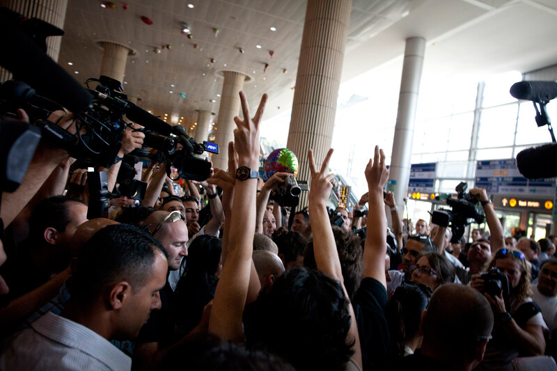 Activists give the "victory" hand gesture as they are surrounded by media