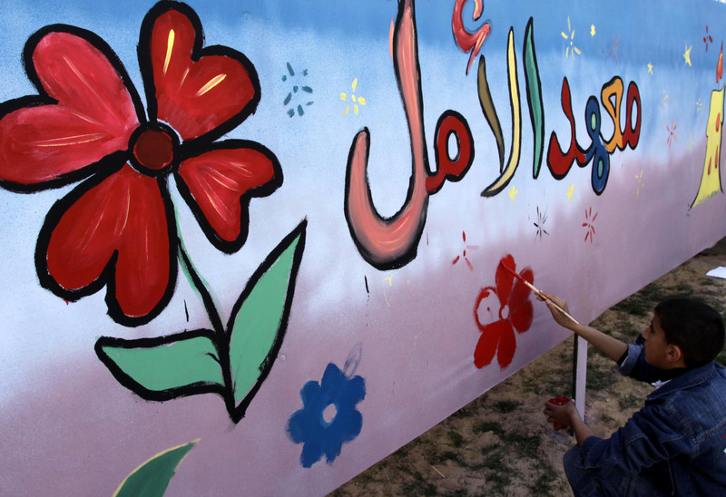 Boy paints mural of flowers on orphanage wall