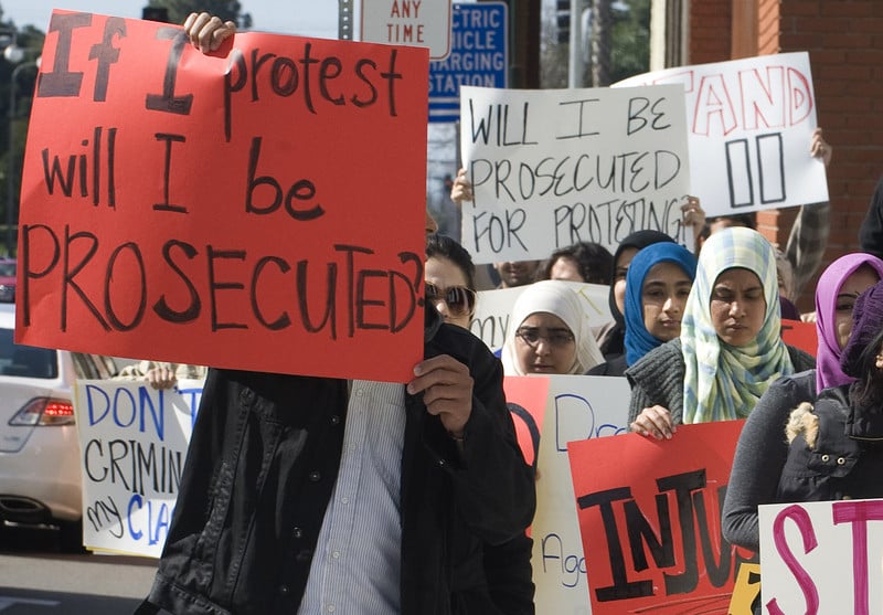 Demonstrators carry signs reading &quot;Will I be prosecuted for protesting?&quot;