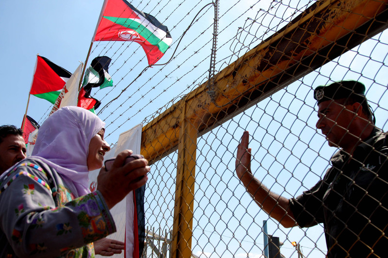 Woman holds sign in front of Israeli prison gates