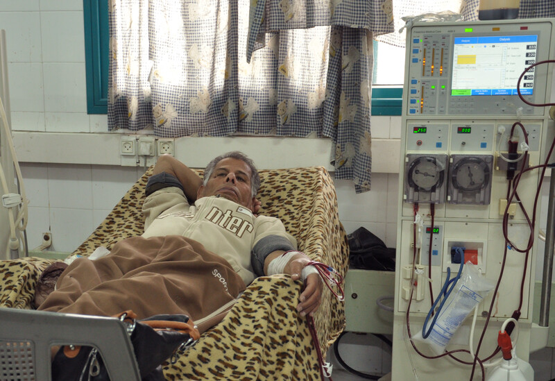 Man lying in bed is hooked up to dialysis machine