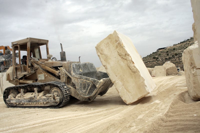 A construction vehicle moves a large block of concrete