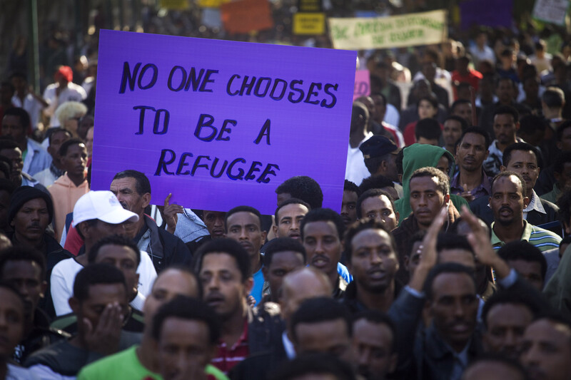 Sign stating &quot;No one chooses to be a refugee&quot; displayed at protest of asylum-seekers