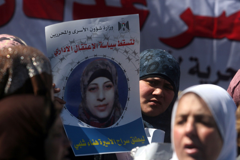 Woman displays poster of Hana al-Shalabi at rally