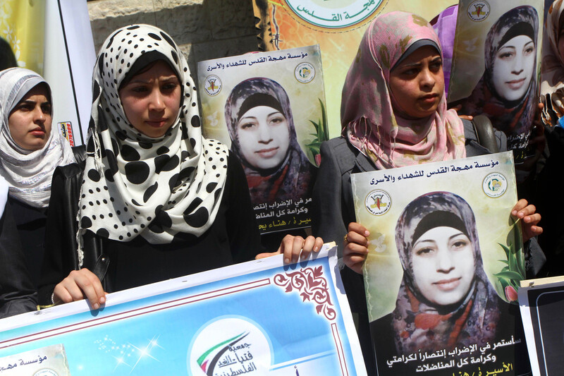 Young women hold posters in solidarity with Hana al-Shalabi