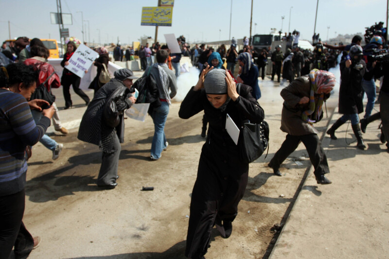 Women duck from tear gas canisters at Women's Day rally