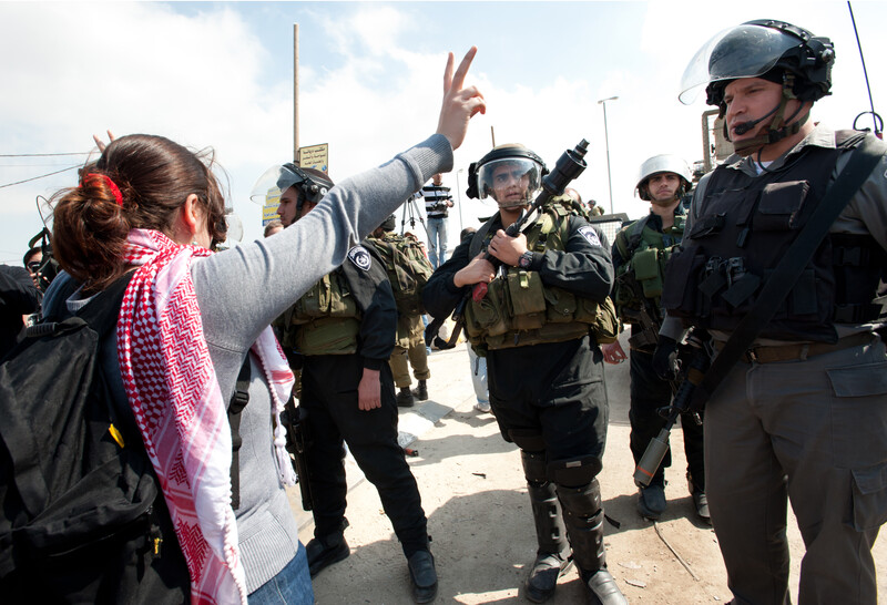 Woman makes &quot;v&quot; for victory hand gesture in front of Israeli soldiers