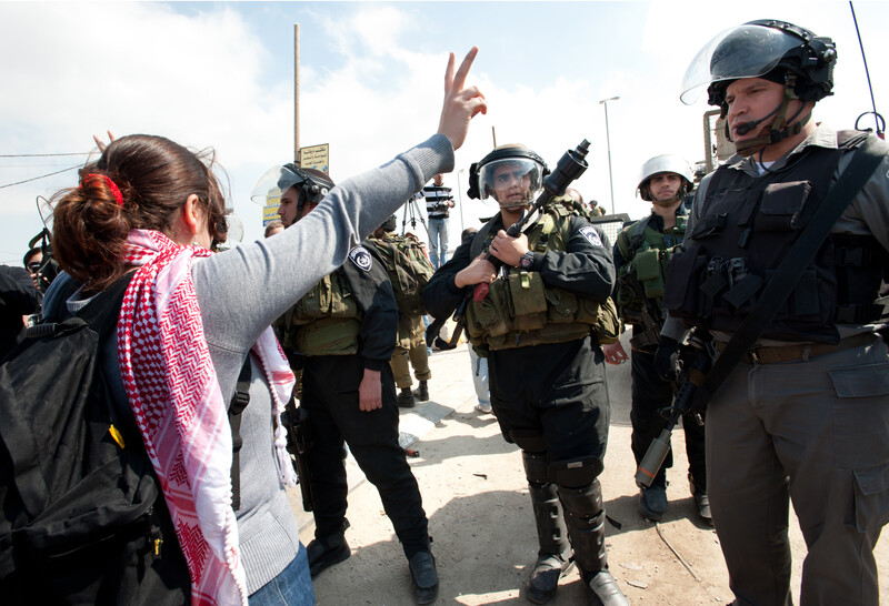 Woman makes "v" for victory hand gesture in front of Israeli soldiers