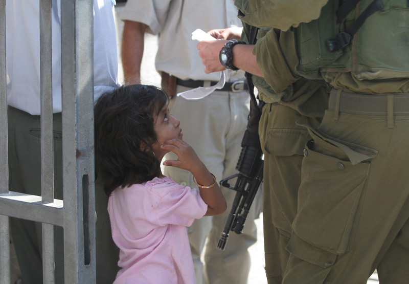 Israeli soldiers examine ID of young girl