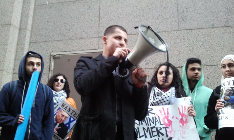 Crowd watches as man speaks into megaphone