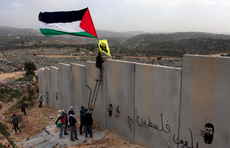 Protesters use ladder to fly flags over West Bank wall
