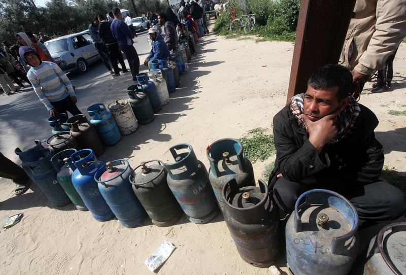Man sits next to queue of gas canisters