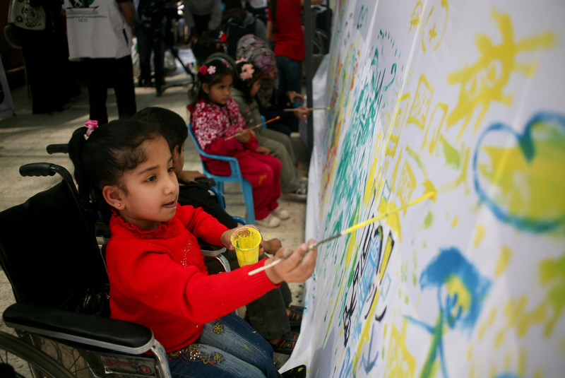 Girl using wheelchair paints on a mural