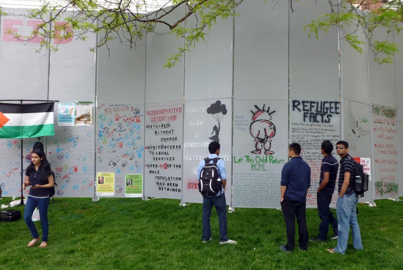 Students look at mock wall displaying messages about Palestine