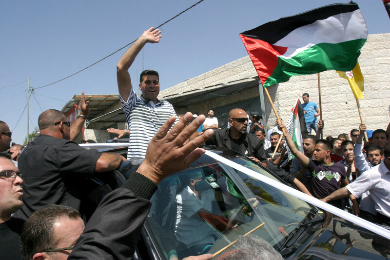 Crowd greets man standing through car moon roof