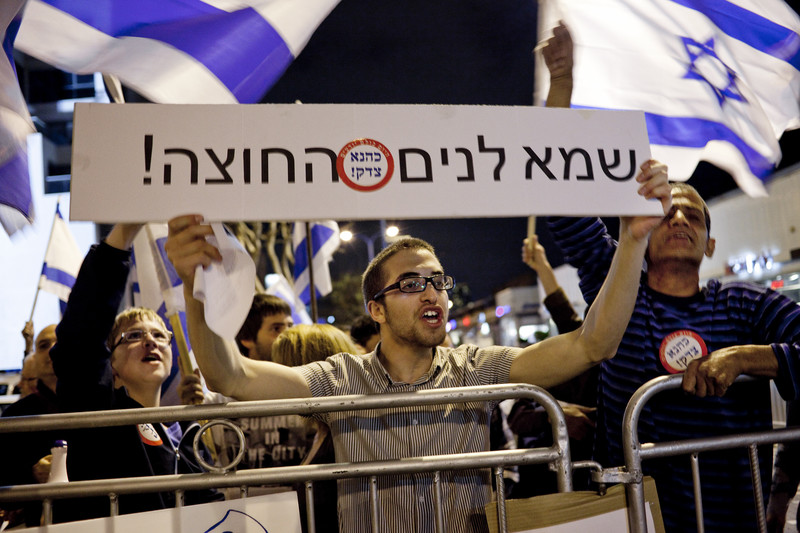 Israelis wave state flag and display signs with ultra-nationalist messaging