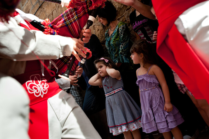 Girl covers her ears with bagpipers in foreground