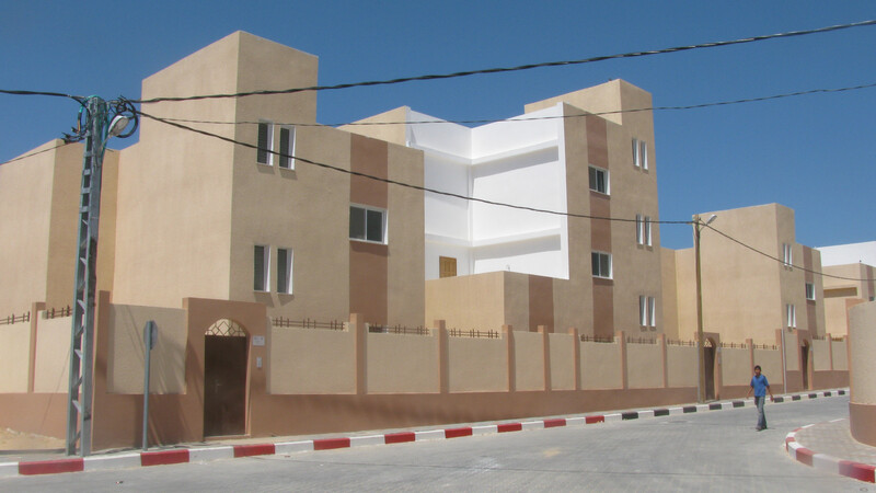 Boy walks past newly-constructed buildings set against blue sky