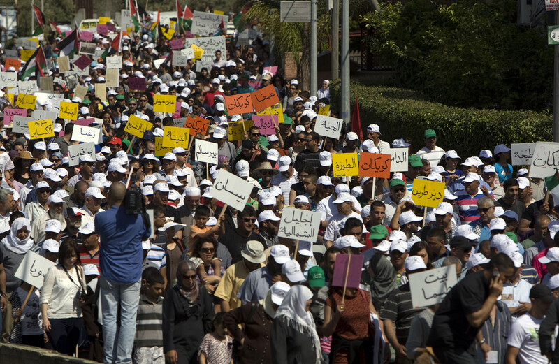 Palestinians march holding signs with the names of destroyed villages